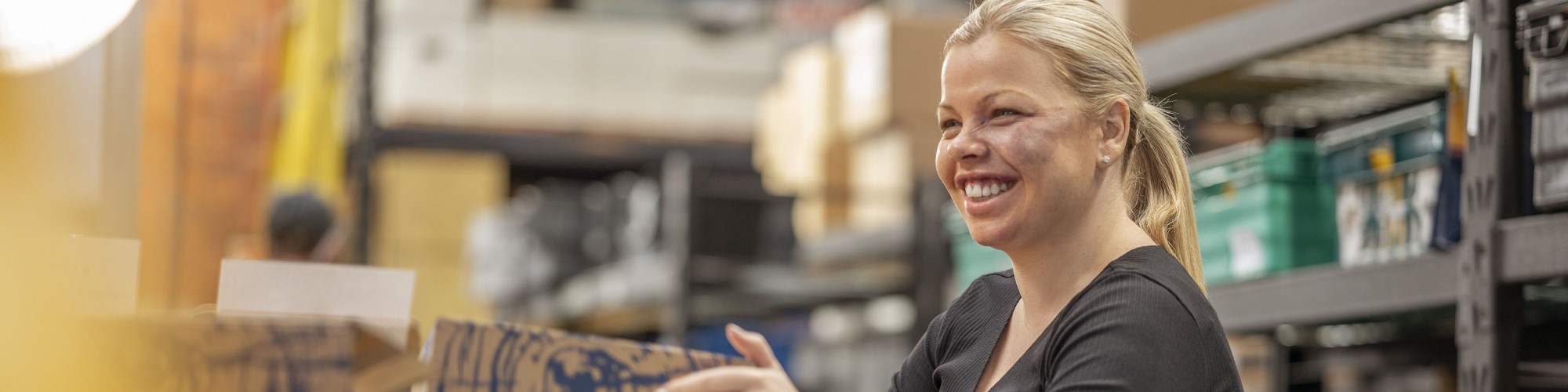 A young woman is boxing products in a factory